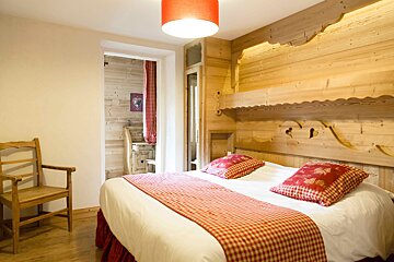 A wooden bedroom with a bed and a chair