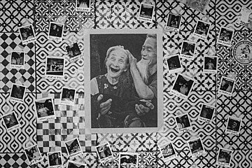 A black and white photo of a man putting a sticker on a woman 's head that says 