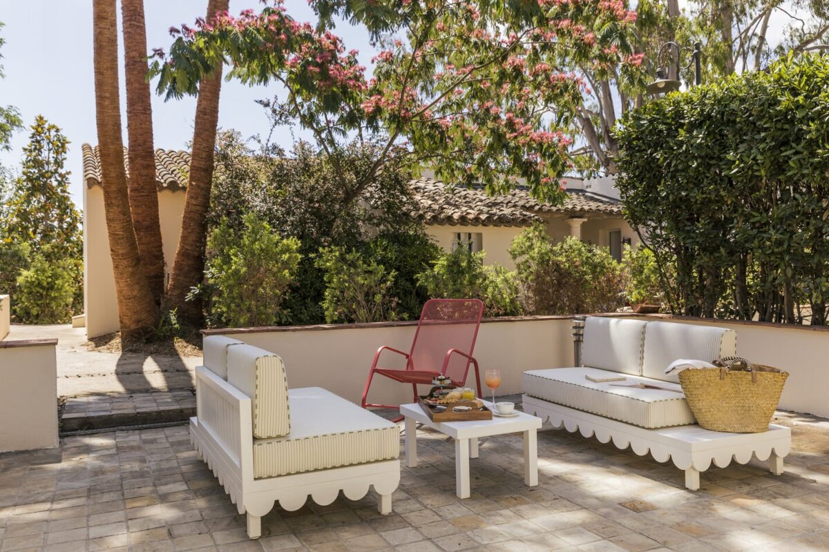 A patio with white furniture and a red chair