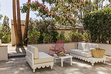 A patio with white furniture and a red chair