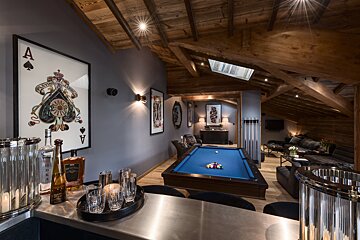 A bottle of vodka sits on a counter next to a pool table