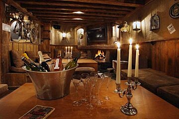 A bucket of champagne sits on a table next to candles