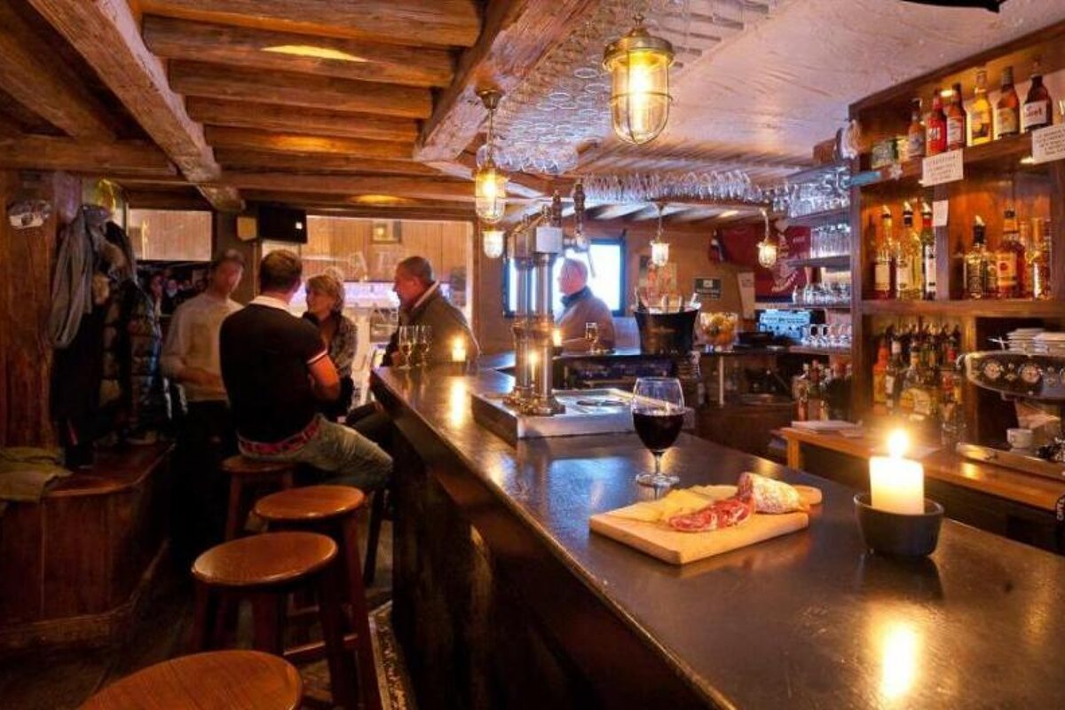 A man sits at a bar with a glass of wine