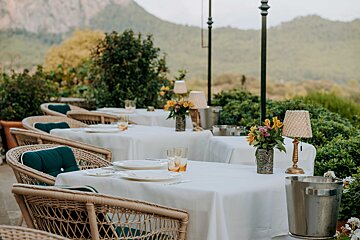 A row of tables with white linens and wicker chairs