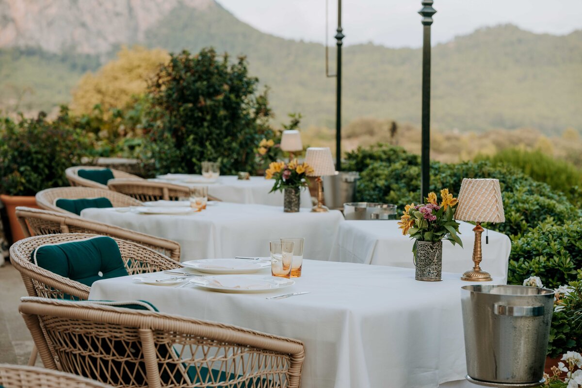 A row of tables with white linens and wicker chairs