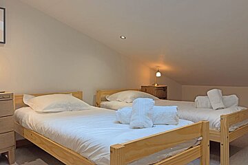 A bedroom with two beds and a picture on the wall