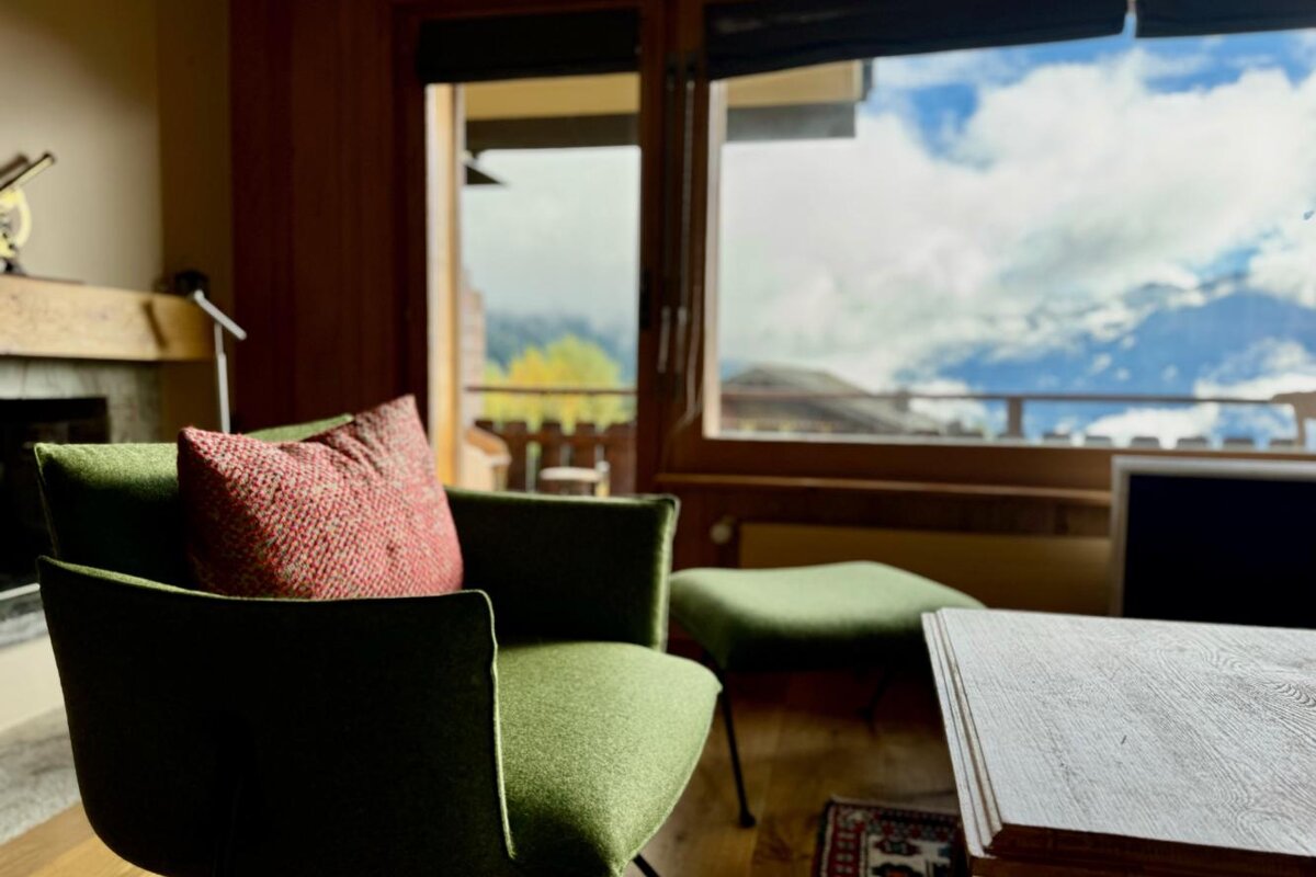 A green chair with a red pillow sits in front of a window