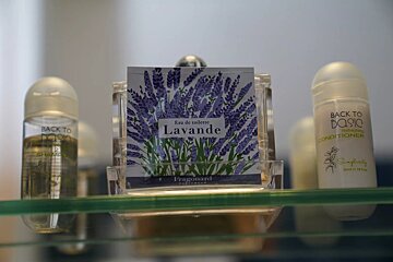 A bottle of lavande perfume sits on a glass shelf
