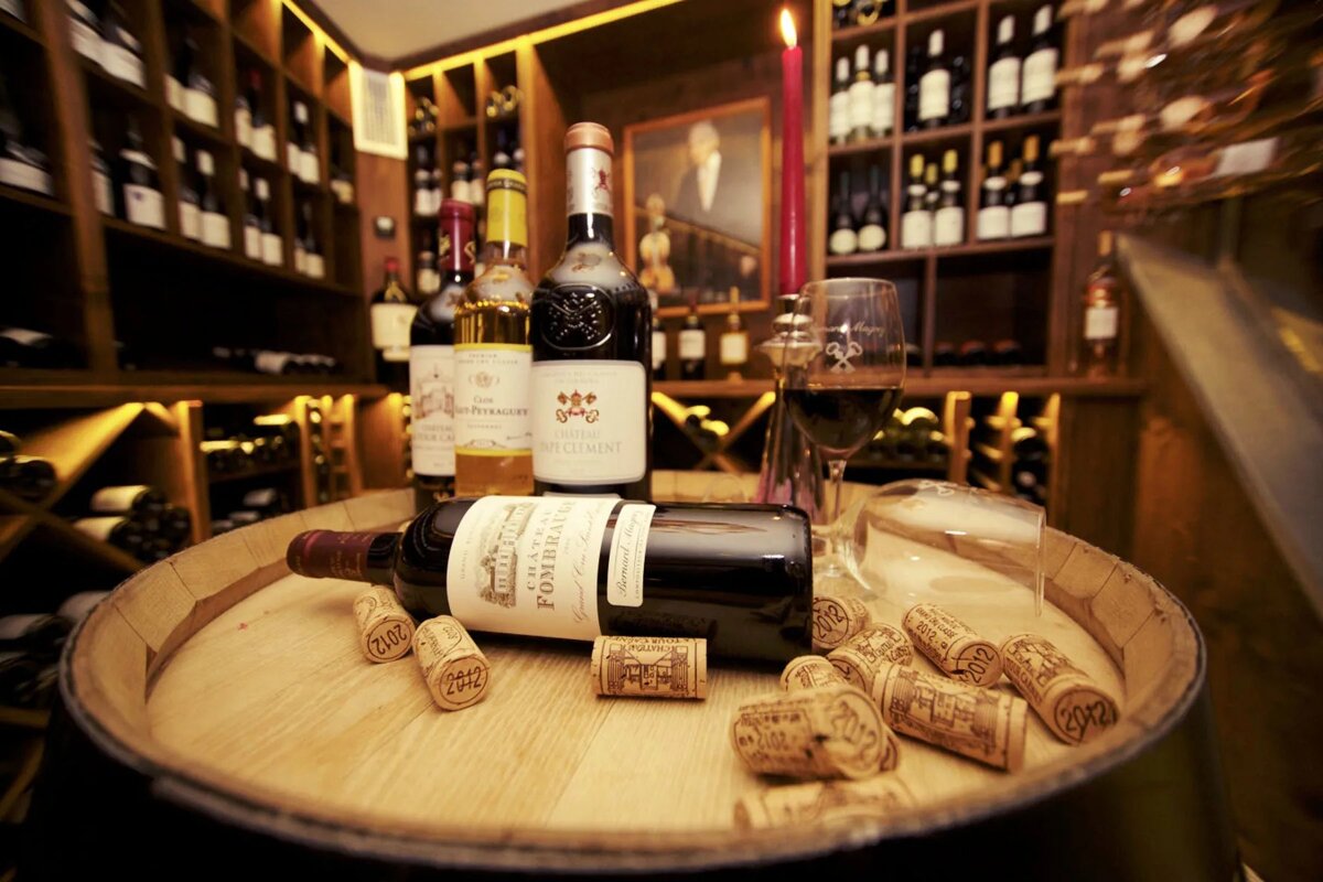 A bottle of pomerol sits on a wooden barrel