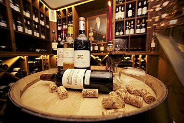 A bottle of pomerol sits on a wooden barrel