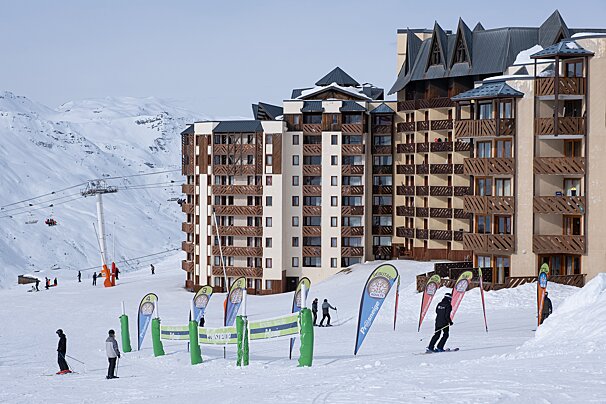 A group of people skiing on a snowy slope in front of a large building