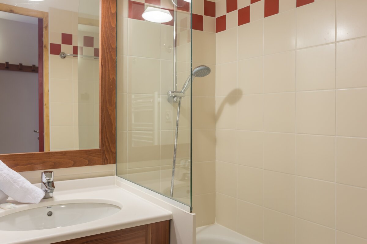 A bathroom with a sink a mirror and a shower