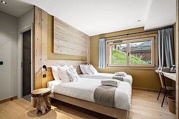 A bedroom with two beds and a window with mountains in the background