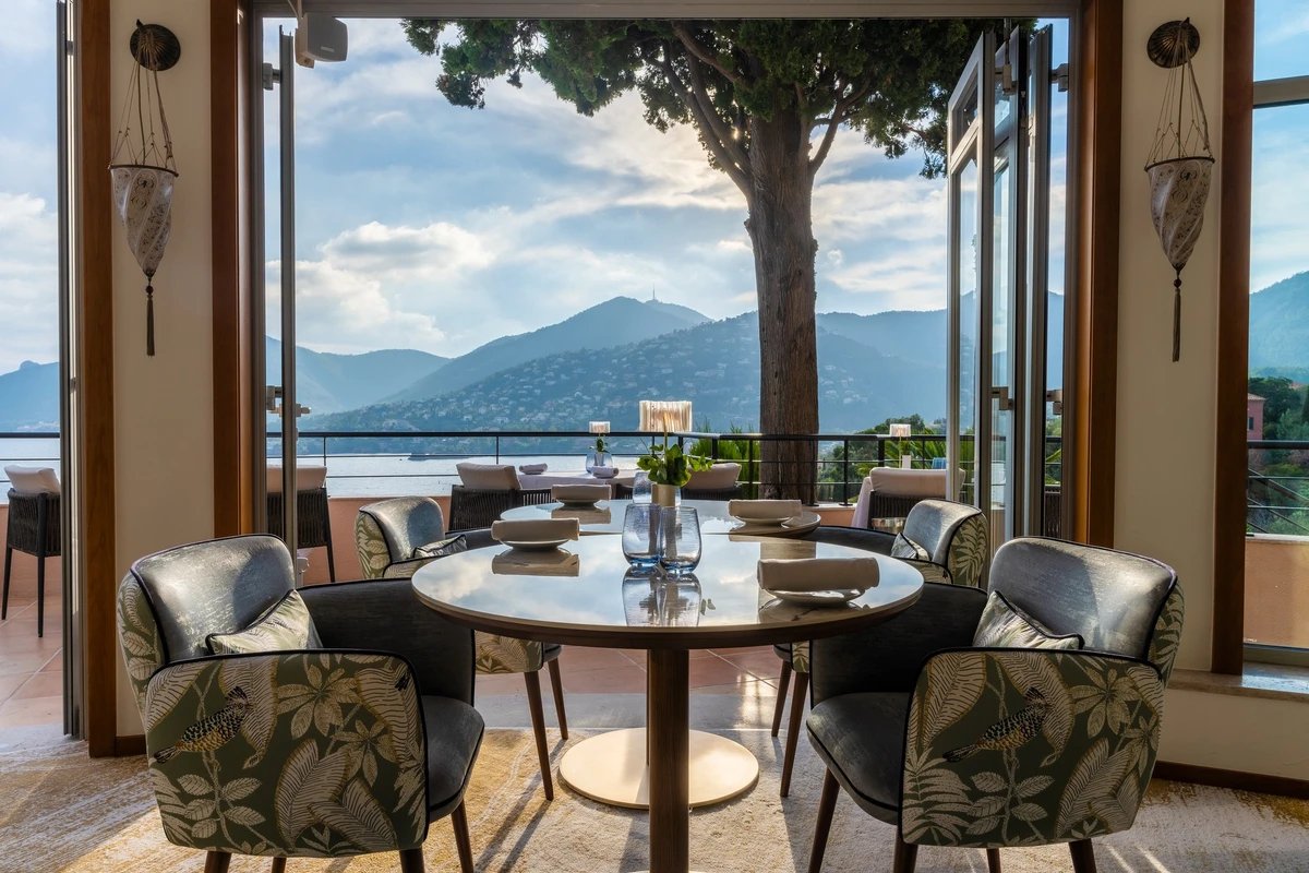 A table and chairs in a room with a view of mountains