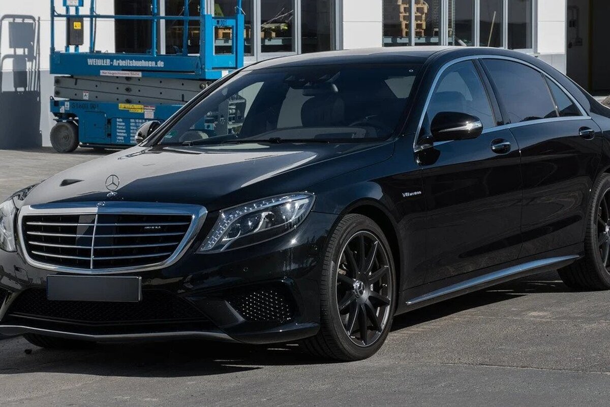 A black mercedes is parked in front of a building