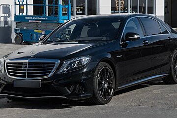 A black mercedes is parked in front of a building