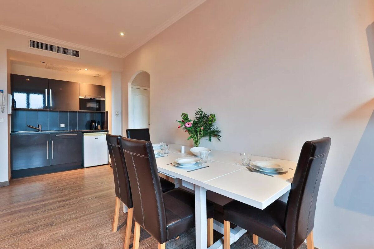 A kitchen with a table and chairs and a vase of flowers