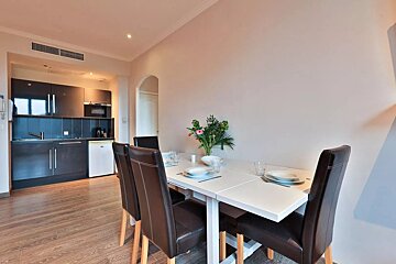 A kitchen with a table and chairs and a vase of flowers