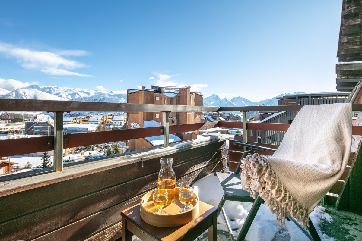 A balcony with a chair and a tray of wine glasses