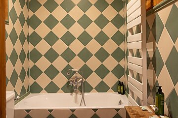 A bathtub in a bathroom with green and white tiles