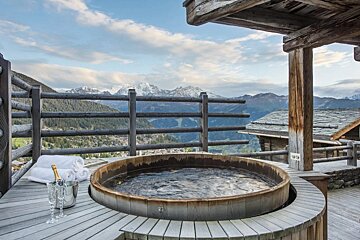 A wooden hot tub with mountains in the background