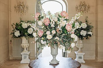 A vase filled with pink and white flowers sits on a table