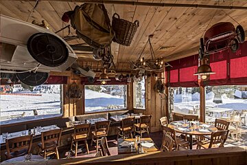 A restaurant with tables and chairs and a view of the snow