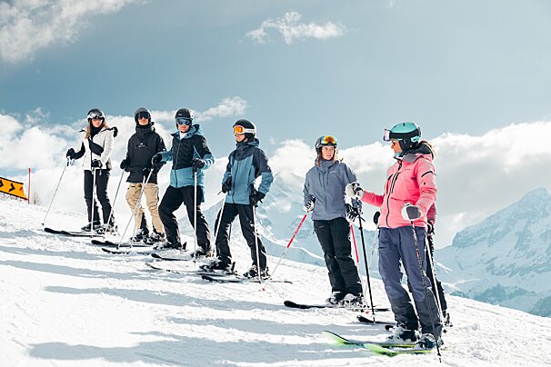 A group of skiers standing on top of a snow covered mountain