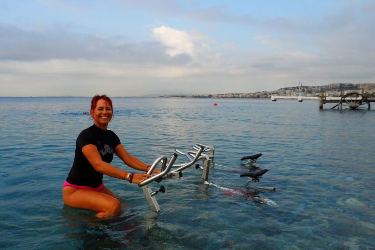a woman smiling whilst sat on an excerise bike