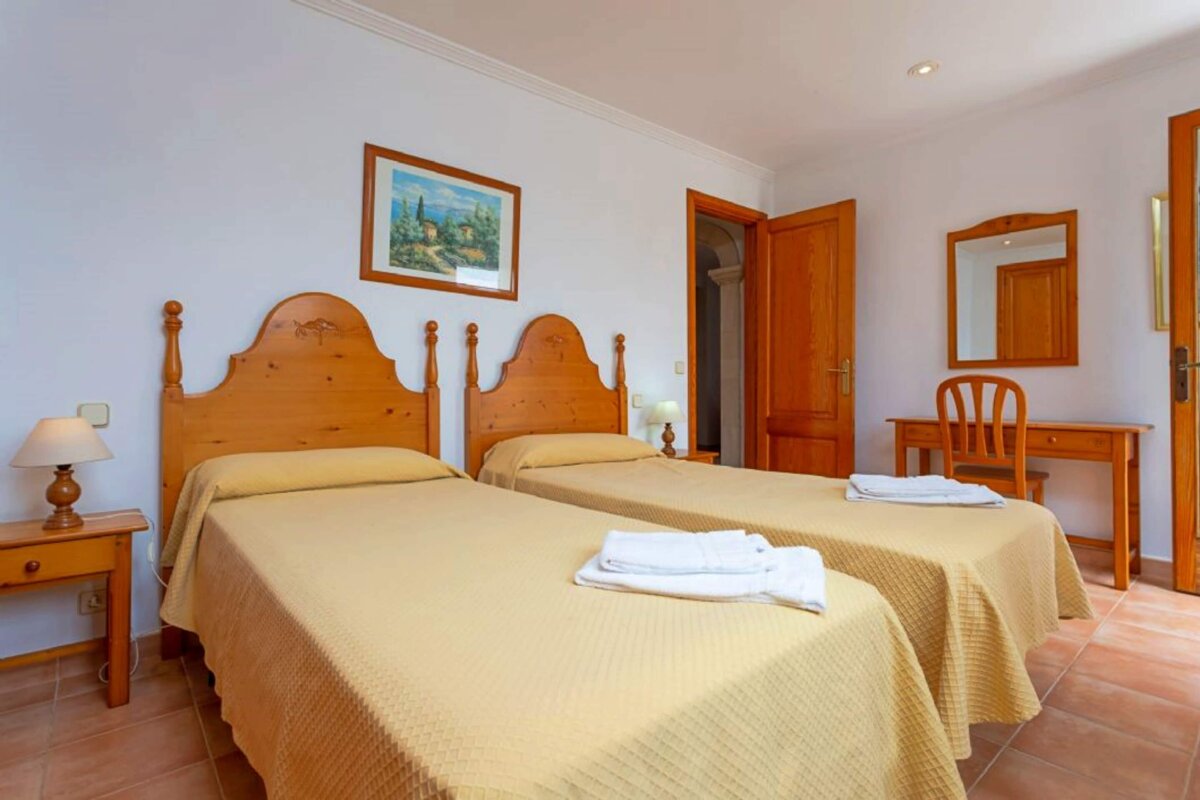 A bedroom with two beds a desk and a mirror