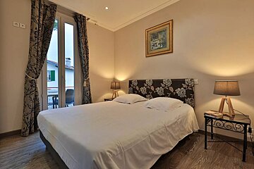 A bedroom with a large bed and two lamps