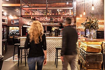 A man and a woman are walking past a bar