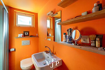 A bathroom with orange walls and a sink that says vjp