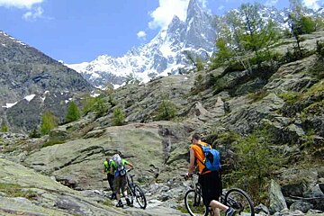 a picture of 2 people mountain biking over some rocks