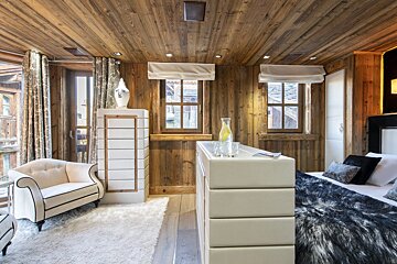 A bedroom with wooden walls and a bed with a fur blanket