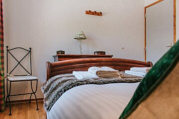 A bedroom with a bed a chair and a lamp