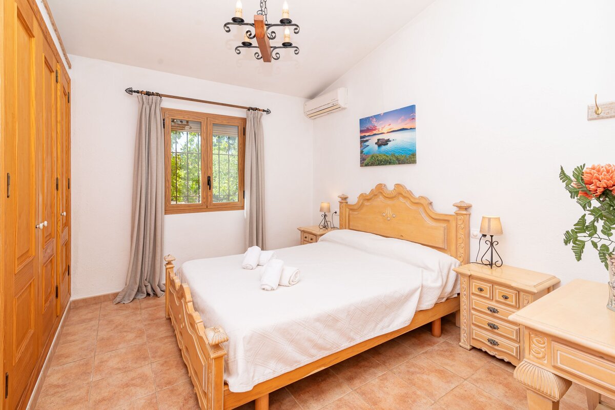 A bedroom with a painting on the wall above the bed