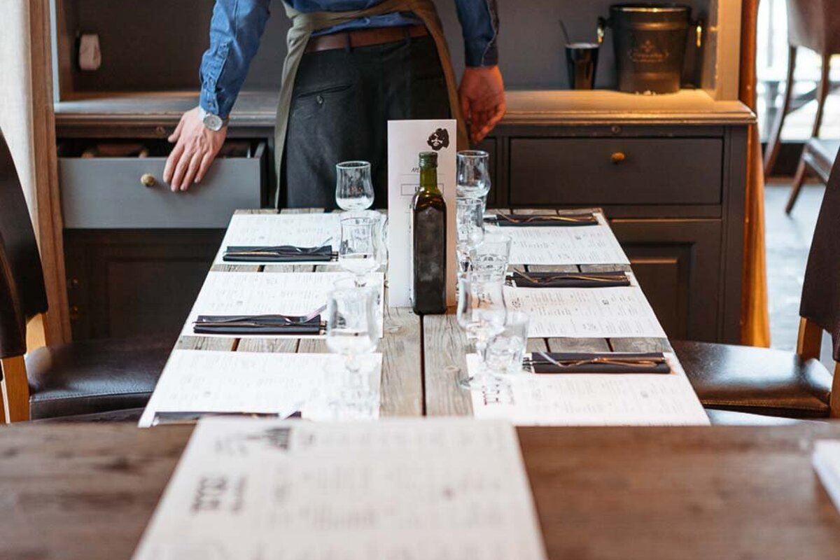 A bottle of olive oil sits on a table in a restaurant