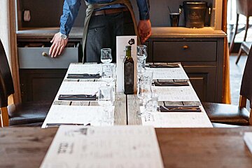 A bottle of olive oil sits on a table in a restaurant