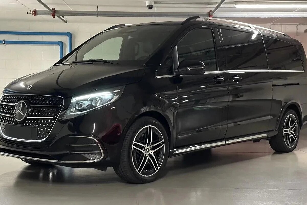A black mercedes van is parked in a garage