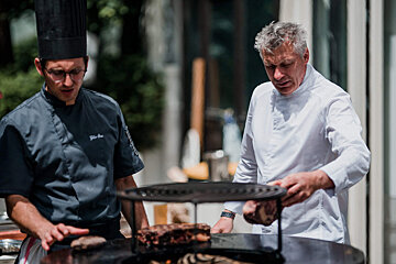 A man in a chef 's uniform is standing next to another man