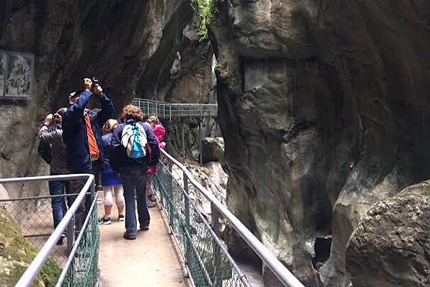 people walking on a metal walkway in a gorge