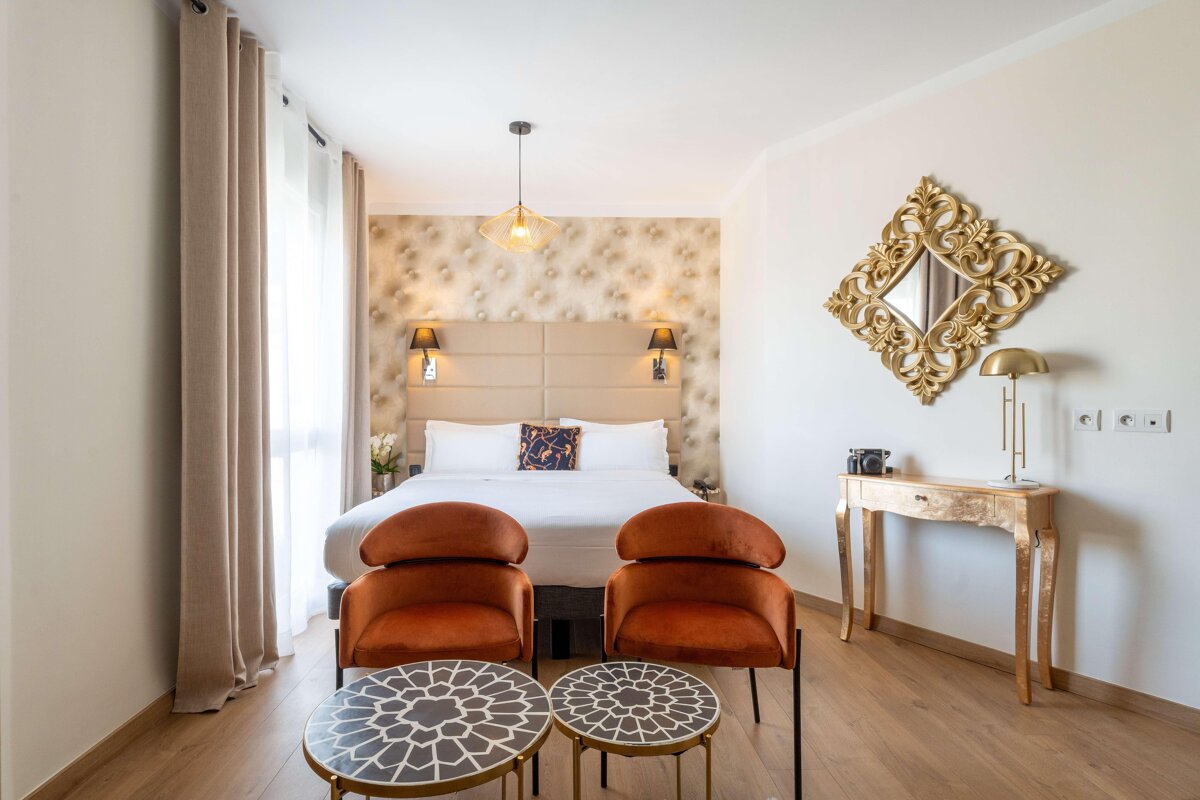 A hotel room with a bed and two chairs