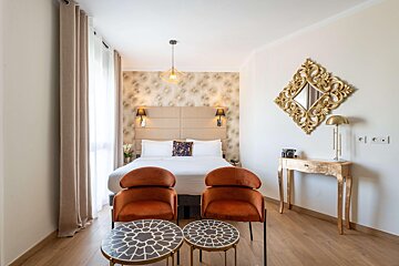 A hotel room with a bed and two chairs