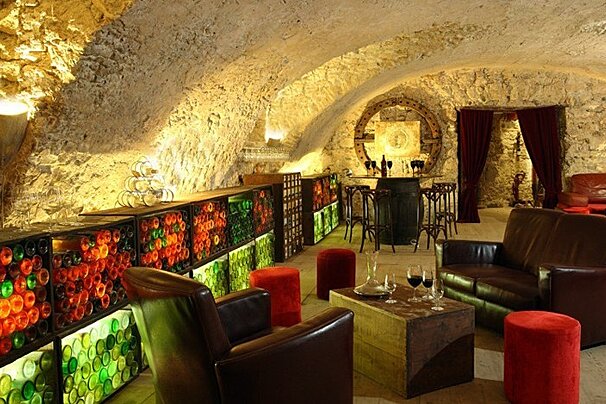 A room with a couch and chairs and a table with wine glasses on it