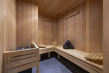 A wooden sauna with a bucket and towels on the benches
