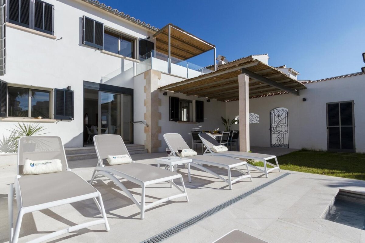 A white house with a swimming pool and lounge chairs