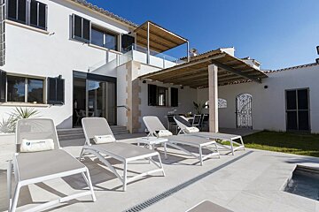 A white house with a swimming pool and lounge chairs