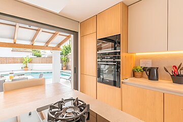 Modern kitchen with wood cabinetry, integrated appliances, and a beautiful outdoor pool view.