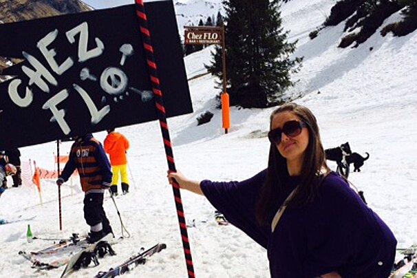a woman holding a flag saying chez flo in avoriaz